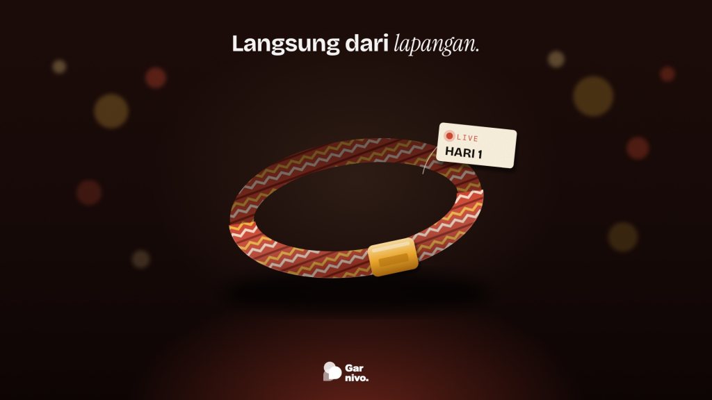 Gelang festival kain bermotif anyaman merah dan amber dengan klip amber, berlabel LIVE HARI 1, melayang di depan bokeh lampu panggung yang gelap.