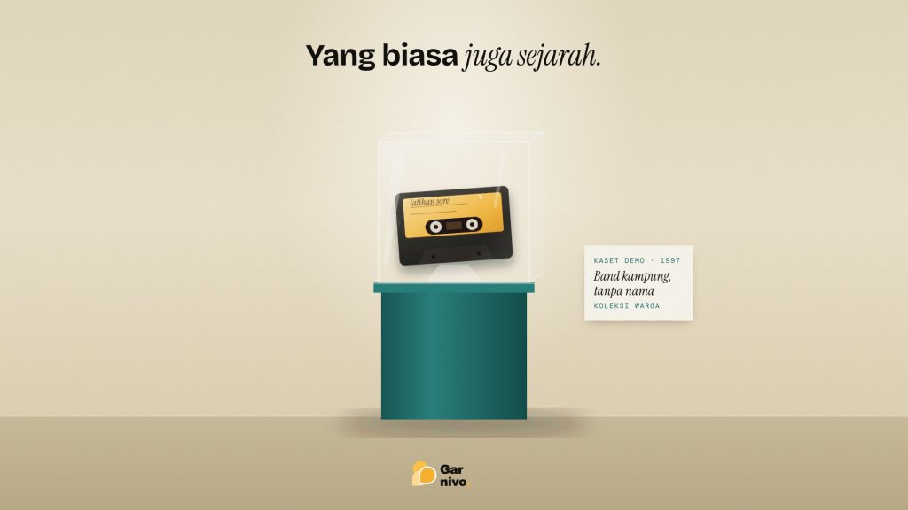 Kaset demo berlabel amber dipajang dalam kotak kaca di atas alas toska, dengan kartu museum bertuliskan band kampung tanpa nama.
