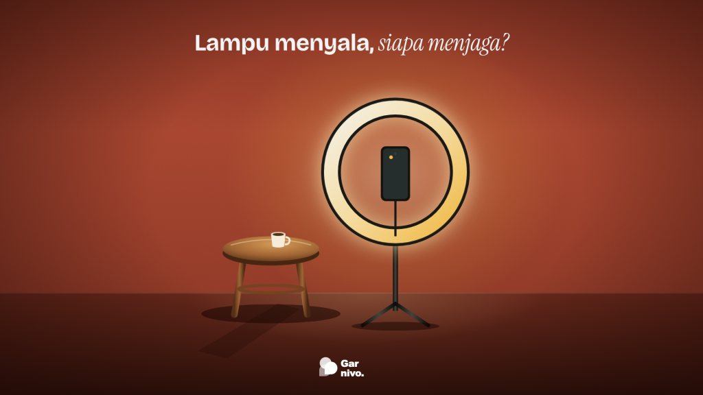 Lampu cincin menyala hangat dengan ponsel di tengahnya, di samping bangku kayu kosong berisi secangkir kopi, di ruang dinding terakota.