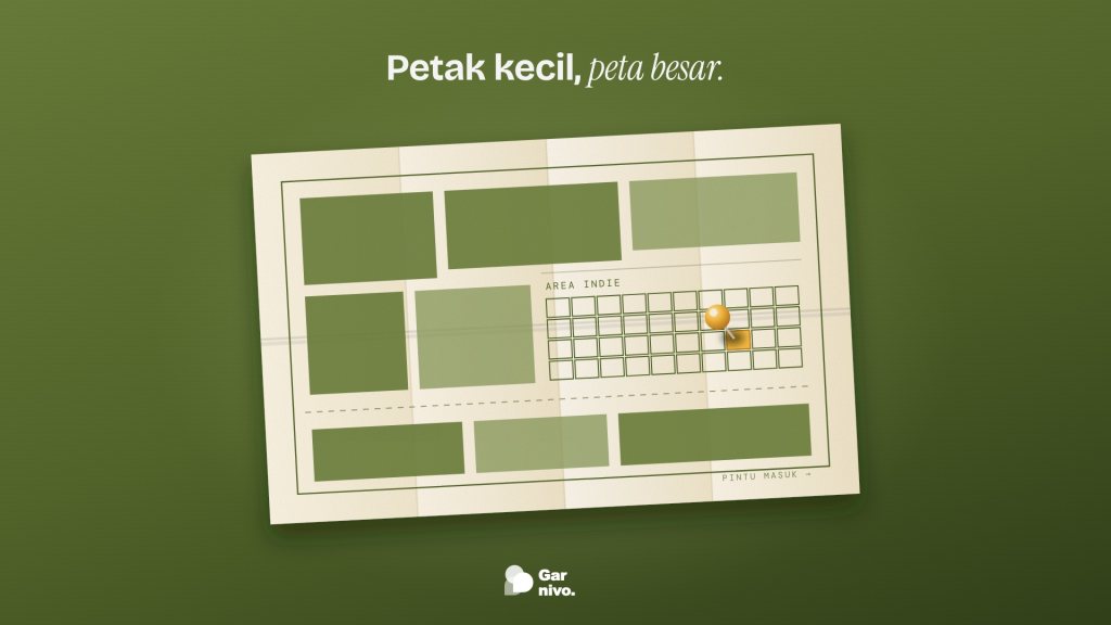 Peta denah pameran di atas meja hijau lumut; stan besar berblok, area indie berpetak kecil, satu petak amber ditandai paku pin.