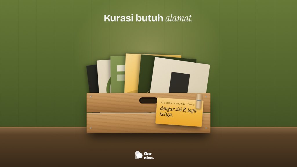 Peti kayu berisi deretan sampul piringan di depan dinding hijau lumut, dengan kartu rekomendasi penjaga toko berwarna amber dijepit di depannya.