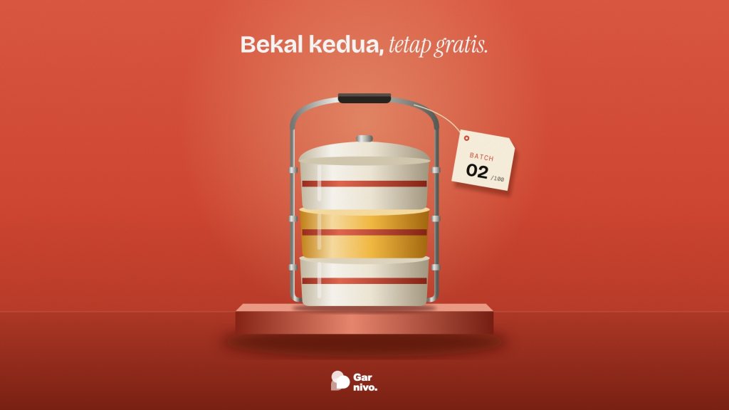 Rantang enamel tiga susun dengan susun tengah berwarna amber, berdiri di atas alas di latar merah, dengan label kertas bertuliskan BATCH 02 dari 100.